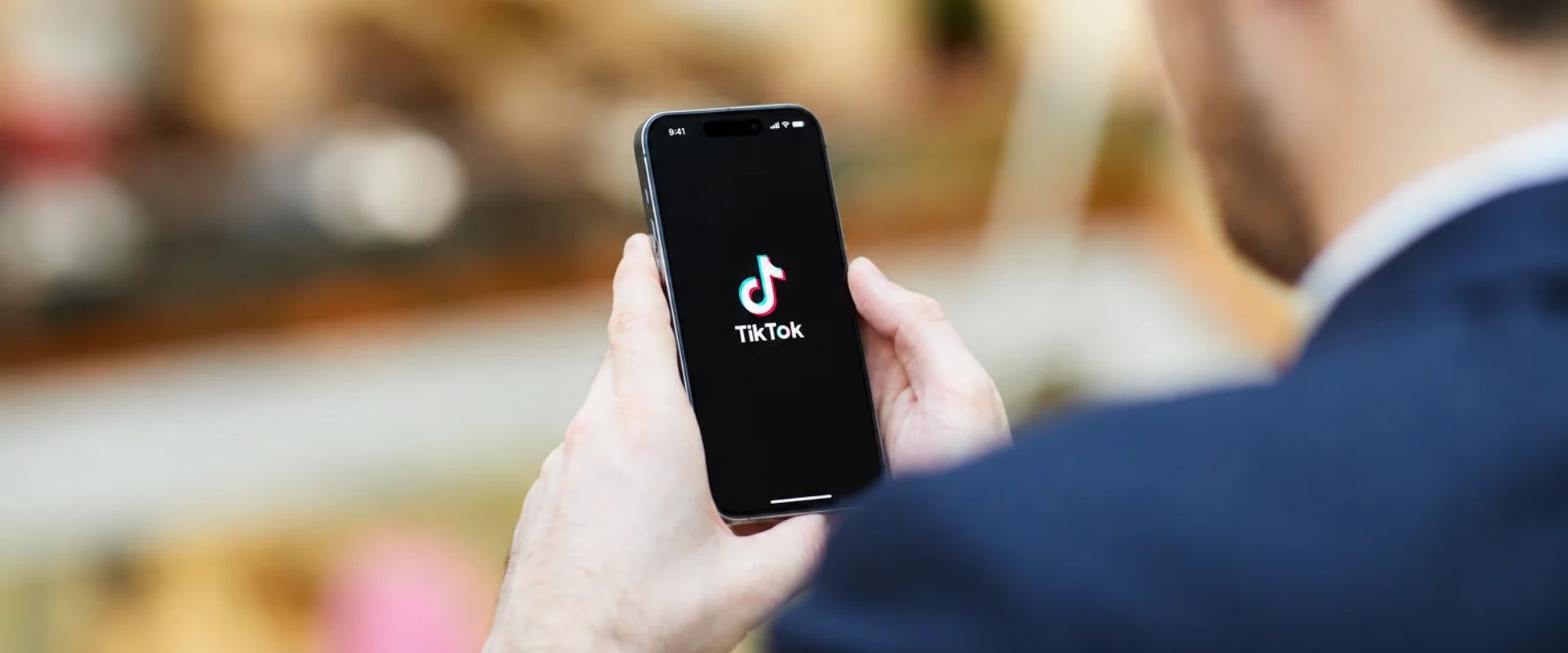 uomo in abito che guarda la schermata di tiktok dal suo cellulare